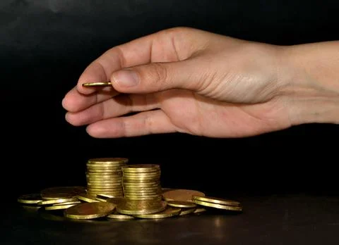 Saving money concept by adding gold coin to a pile of coins Stock-Fotos