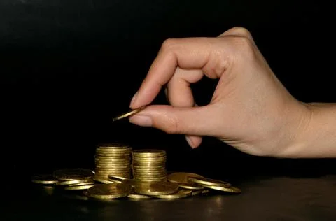 Saving money concept by adding gold coin to a pile of coins. Black background Foto stock