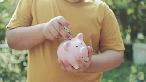 Saving money concept, Little boy hand putting money coin into piggy bank.  Stock Footage 149085508