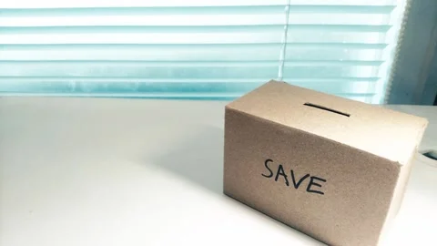 Saving money by putting coins in a box savings Stock Footage 276339167