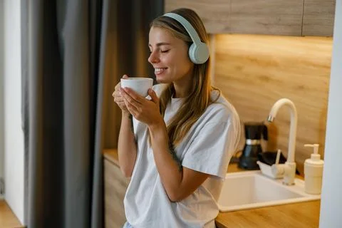 Savoring a Delicious Cup of Coffee While Wearing Headphones in a Stylish Modern Stock Photos