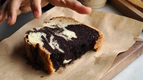 Savoring a delicious slice of marble cake while sitting at a wooden table Stock Footage 346990146