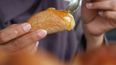 Savoring the delightful experience of freshly baked bread topped with honey Stock Footage 345953249
