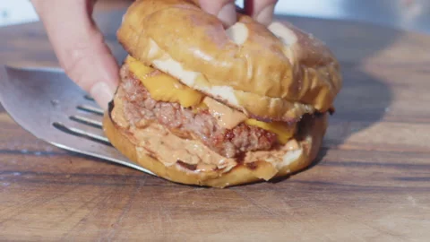 Savoring Slowly: Slow Motion Cheeseburger on Wooden Board Video stock 258299451