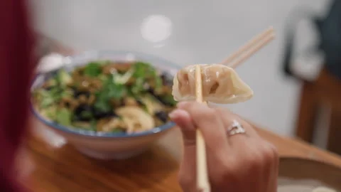 Savory Asian dumpling being lifted with chopsticks in greens. Detailed scene Stock Footage 342279922