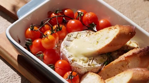 A savory dish featuring baked Camembert cheese, surrounded by fresh cherry Stock Footage 330616408