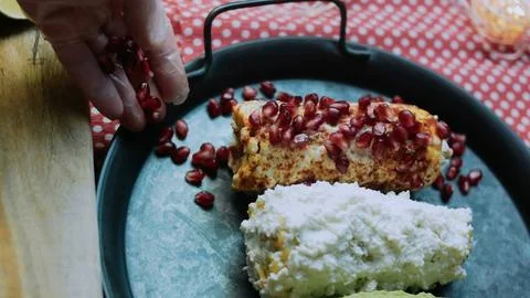 Savory food study: adding pomegranate seeds to elote Stock Photos