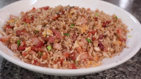 Savory ham fried rice with egg and vegetables served on a white plate 動画素材 325656844