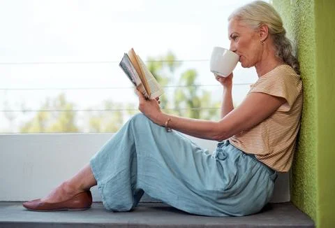 Savour every moment of serenity. a mature woman reading a book and having coffee Stock Photos