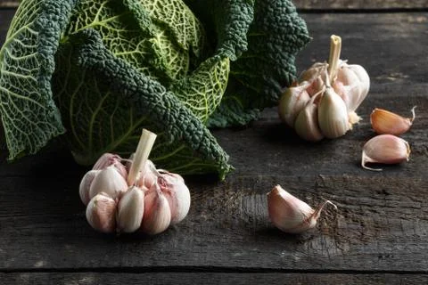 Savoy cabbage and fresh garlic on a dark wooden table Stock Photos