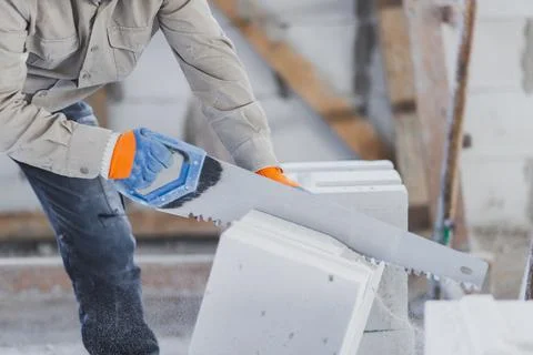 Sawing an autoclaved aerated block with a hand saw at a construction site Stock Photos