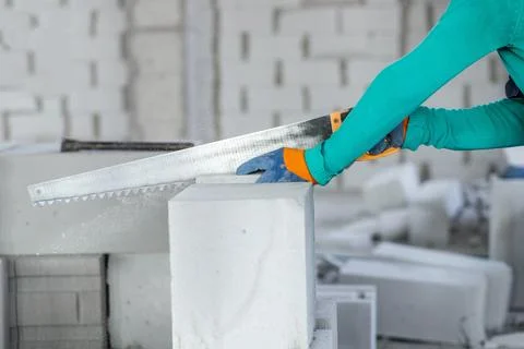Sawing an autoclaved aerated gas block with a hand saw at a construction site Stock Photos