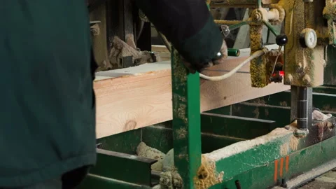 Sawing plank from a log in old dirty sawmill by electrical bandsaw Stock Footage 228952497