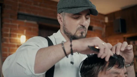 SBarber with a beard and a cap. Barber makes a haircut with scissors. Stock Footage 132282572