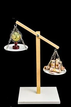 A scale with a globe on one side and a pile of money on the other Stock Photos