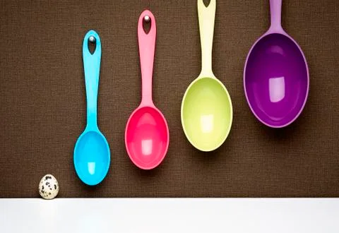 Scale of spotted egg and hanging multicolor measuring spoons Stock Photos