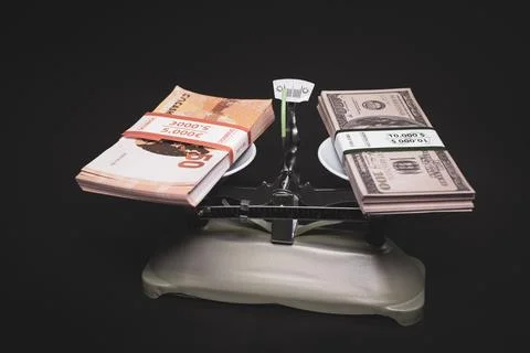 On the scale there is a bundle of dollar banknotes on one side and a bundle o Stockfoto's