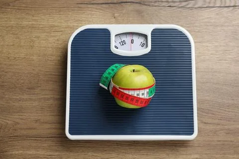 Scales with apple and measuring tape on wooden table, top view. Weight loss Stock Photos