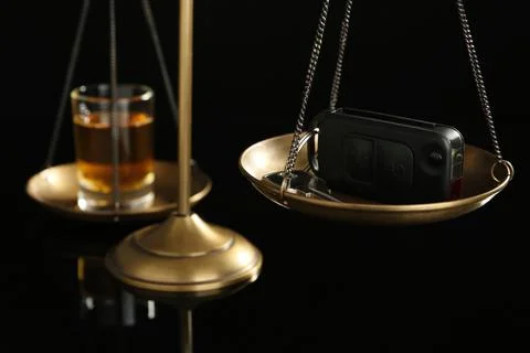 Scales of justice with car key and alcohol on black background, closeup. Drun Stock Photos