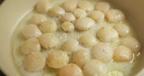 Scallops being turned to achieve an even golden sear, homemade seafood cooking Видео 328338032