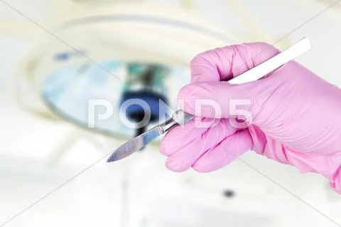 Scalpel in surgeon's hand under lamp Stock Photos