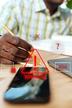 Scam call alert on smartphone with warning symbols and person writing notes Stock Photos
