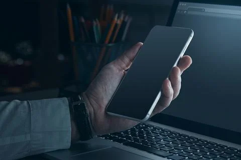Scam call sms message received on a smartphone while using a laptop at night Foto stock