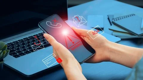 Scam call warning message on a mobile phone near a laptop and office items Stock Photos