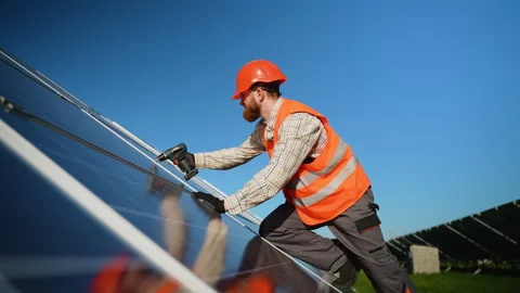 Scandinavian technician installing solar panels in a large solar farm Stock Footage 314404992