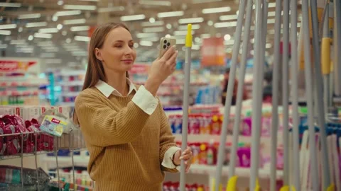 Scanning a broom and a saw using a smartphone in a busy store setting with Vídeo Stock 293675447