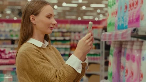 Scanning laundry conditioner with a smartphone in a bright supermarket aisle 스톡 동영상 293675219