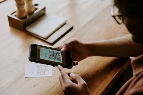Scanning QR Code with Smartphone Device on Wooden Table 库存照片