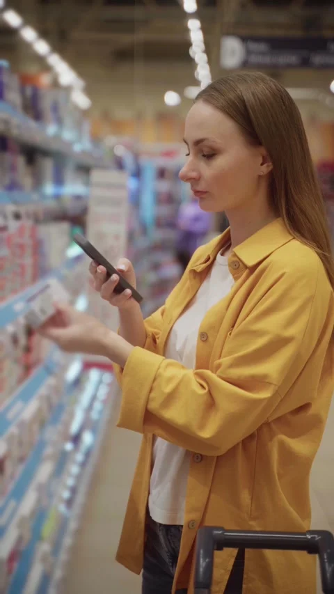 Scanning toothpaste options while shopping in a grocery store for oral care Stock Footage 305416497