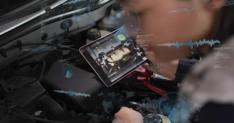 Scanning woman in dark jacket referencing tablet at hood, with battery red Stock Photos