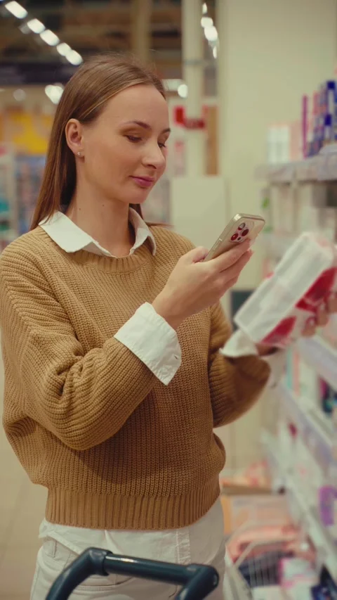 Scanning women's pads with smartphone technology while shopping in a retail Stock Footage 293674567