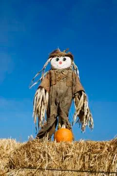 Scarecrow on hay stack with a blue sky. Stock Photos
