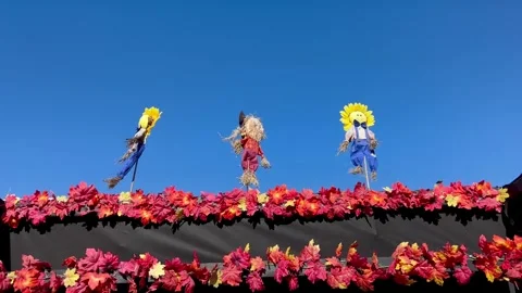 Scarecrows Blowing in the Wind Above Autumn Foliage Display Stock Footage 348317795