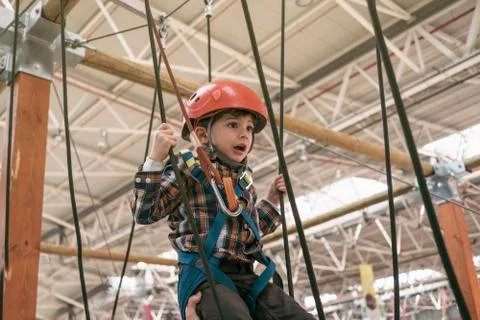 Scared 4 year old boy plays in rope circuit and boards, showing his ability Stock Photos