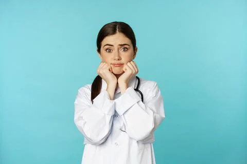 Scared and worried woman doctor in white coat, looking anxious and insecure Stock Photos
