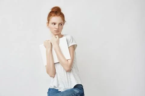 Scared beautiful redhead girl holding book looking in side Stock Photos