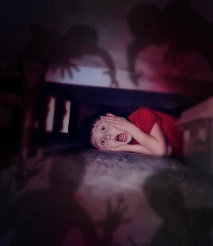 Scared boy looking at night shadows under bed Stock Photos