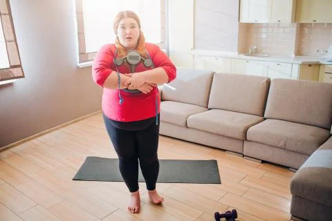 Scared confused young plus size model look on camera. Holding weight scale in Foto stock