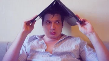 Scared crazy man sits covering his head with a laptop Stock Footage 86163734