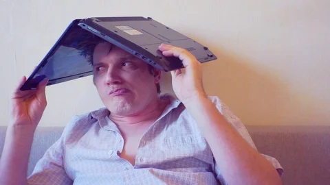 Scared crazy man sits covering his head with a laptop Stock Footage 86165010