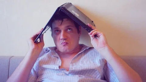 Scared crazy man sits covering his head with a laptop Stock Footage 86165260
