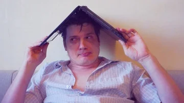 Scared crazy man sits covering his head with a laptop Stock Footage 86166051