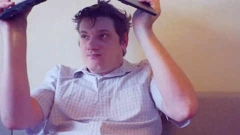 Scared crazy man sits covering his head with a laptop Stock Footage 86166350