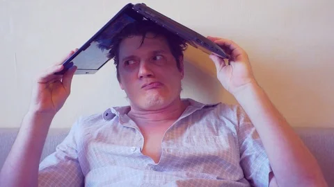 Scared crazy man sits covering his head with a laptop Stock Footage 86166589