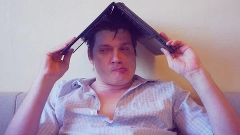 Scared crazy user sitting with laptop on head Stock Footage 86164606