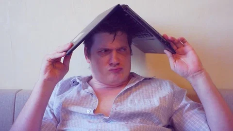 Scared crazy user sitting with laptop on head Stock Footage 86165717